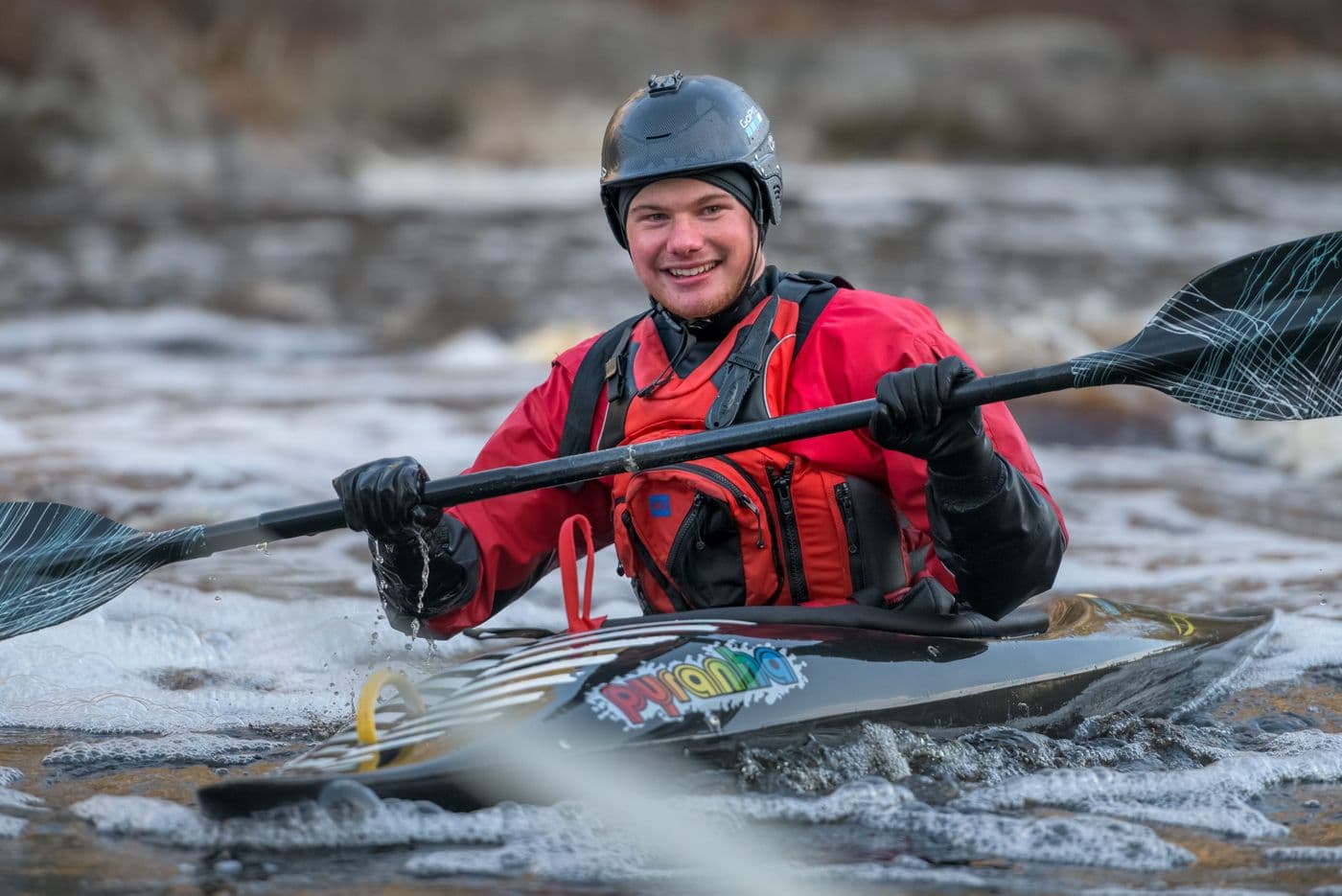 A lady and a dog sitting in a tent overlooking the water.