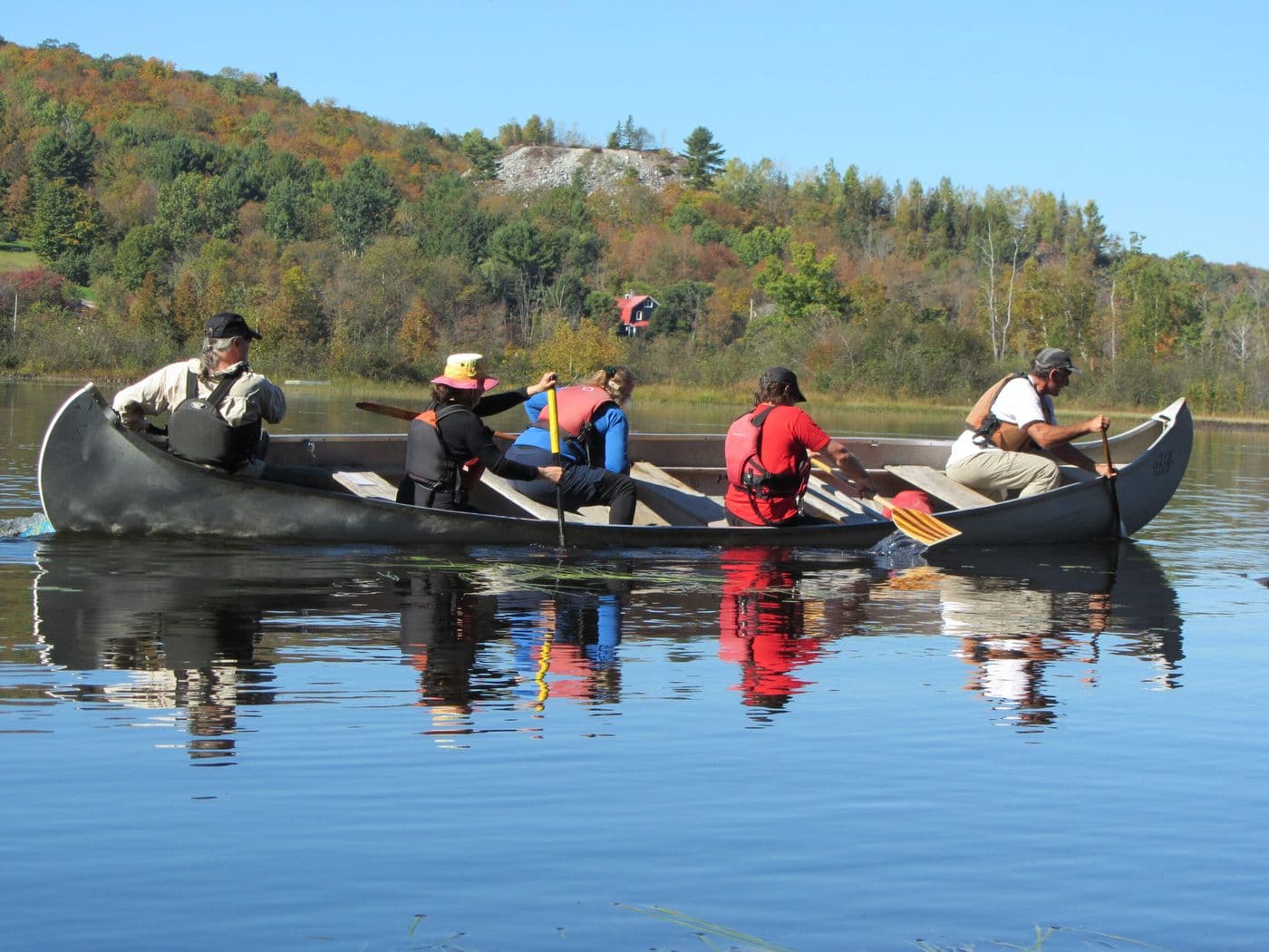 A lady and a dog sitting in a tent overlooking the water.