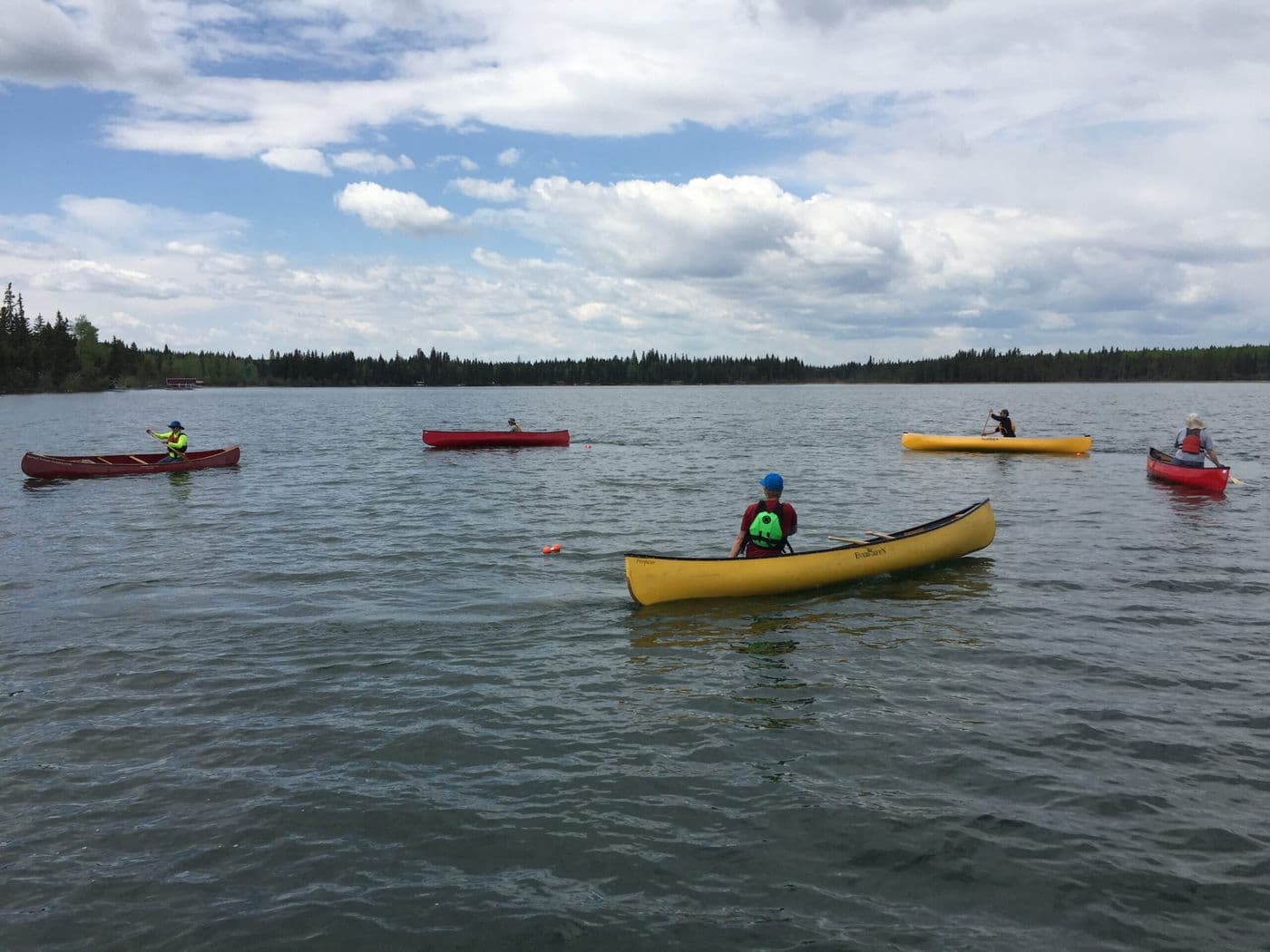 A lady and a dog sitting in a tent overlooking the water.
