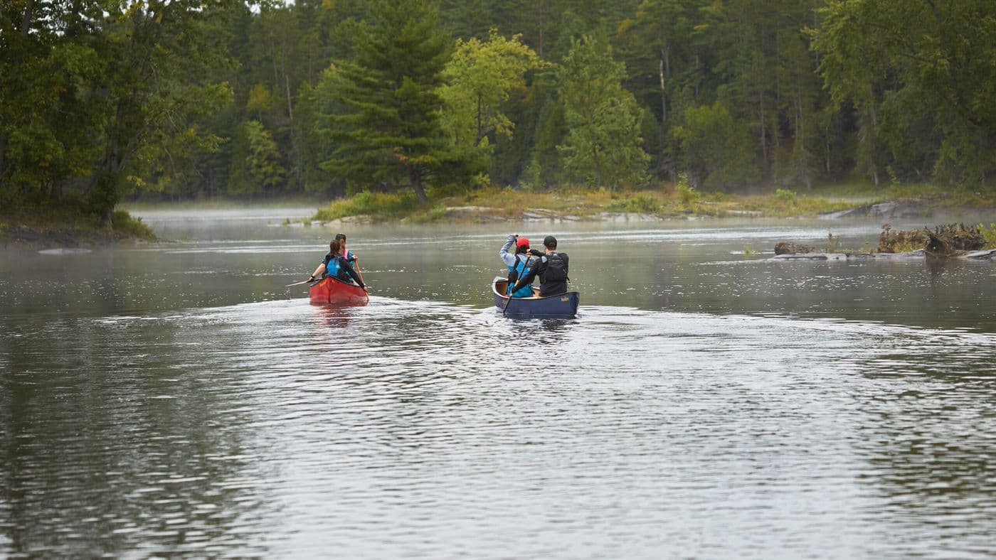 A group of people in two canoes paddling down a river.